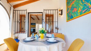 Mesa de comedor con mantel blanco, servilletas estampadas azules y sillas amarillas.