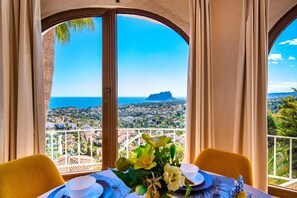 Ein Essbereich mit einem Tisch für zwei Personen, Blick aufs Meer und ein ferner Berg.