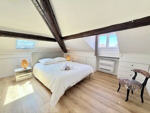 Een slaapkamer met een bed, nachtkastje, stoel, dakraam en een raam.