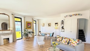 Un soggiorno spazioso con camino, divano, zona pranzo e una scalinata che conduce a un piano superiore.