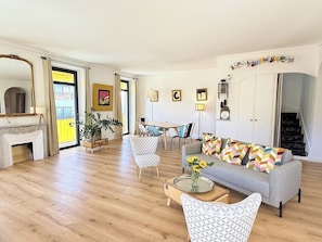 Ein geräumiges Wohnzimmer mit Kamin, einer Sofagarnitur, einem Essbereich und einer Treppe, die zu einer oberen Etage führt.