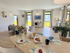 Ein Essbereich mit Tisch für zwei Personen, einer Couch und Blick ins Freie.