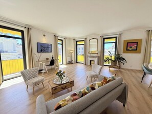 Ein geräumiges Wohnzimmer mit einer Couch, Sesseln, einem Couchtisch und einem Kamin.