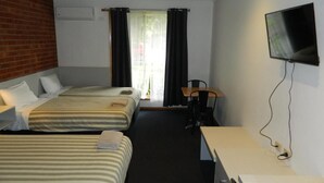 Une chambre d’hôtel avec deux lits, un bureau, une chaise, une télévision et une fenêtre avec des rideaux.