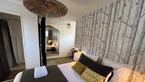 Una camera d'albergo con un letto, uno specchio, una parete decorata con un motivo floreale e un lampadario.