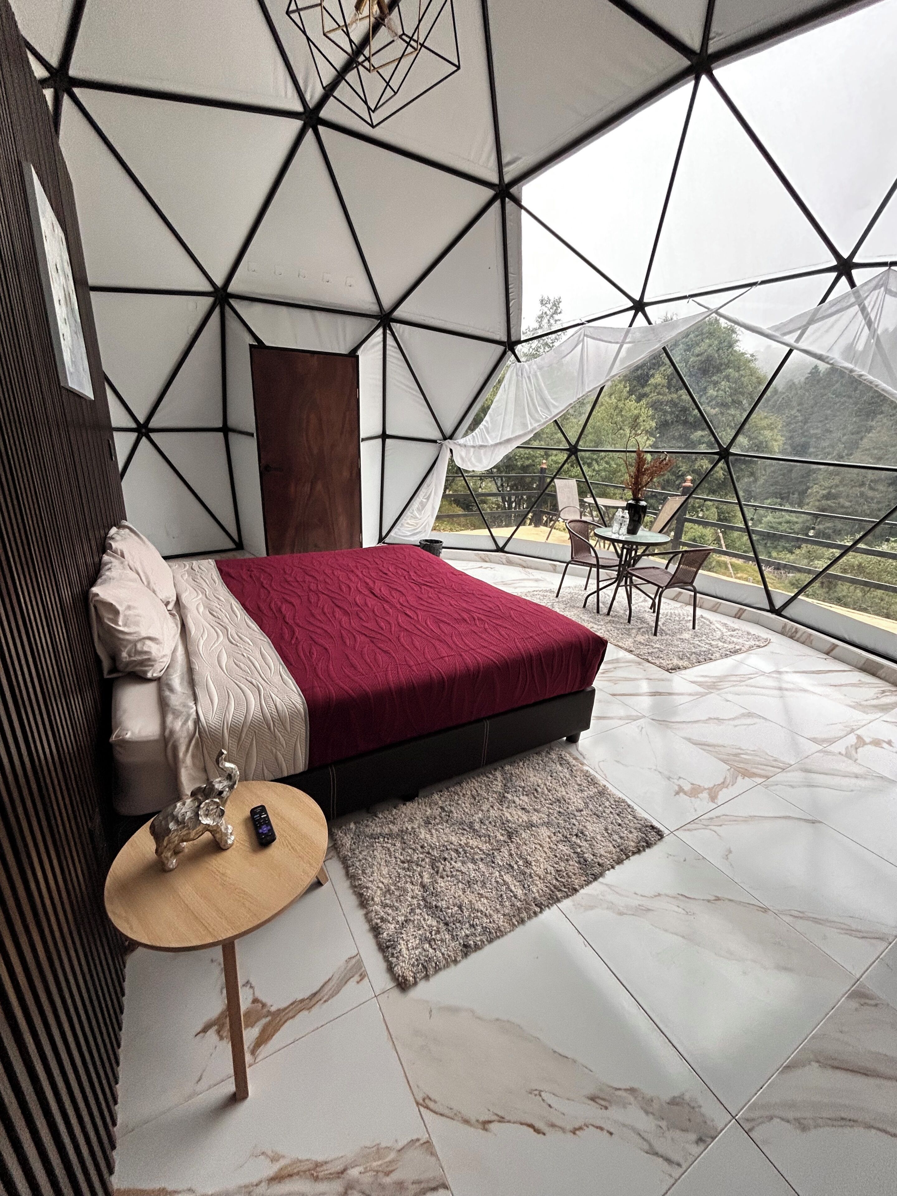 Una habitación moderna con una cama, una mesita y vistas a través de un ventanal de diseño.