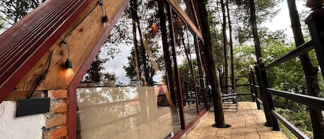 A covered outdoor area with a wooden structure, metal railings, and a stone floor.
