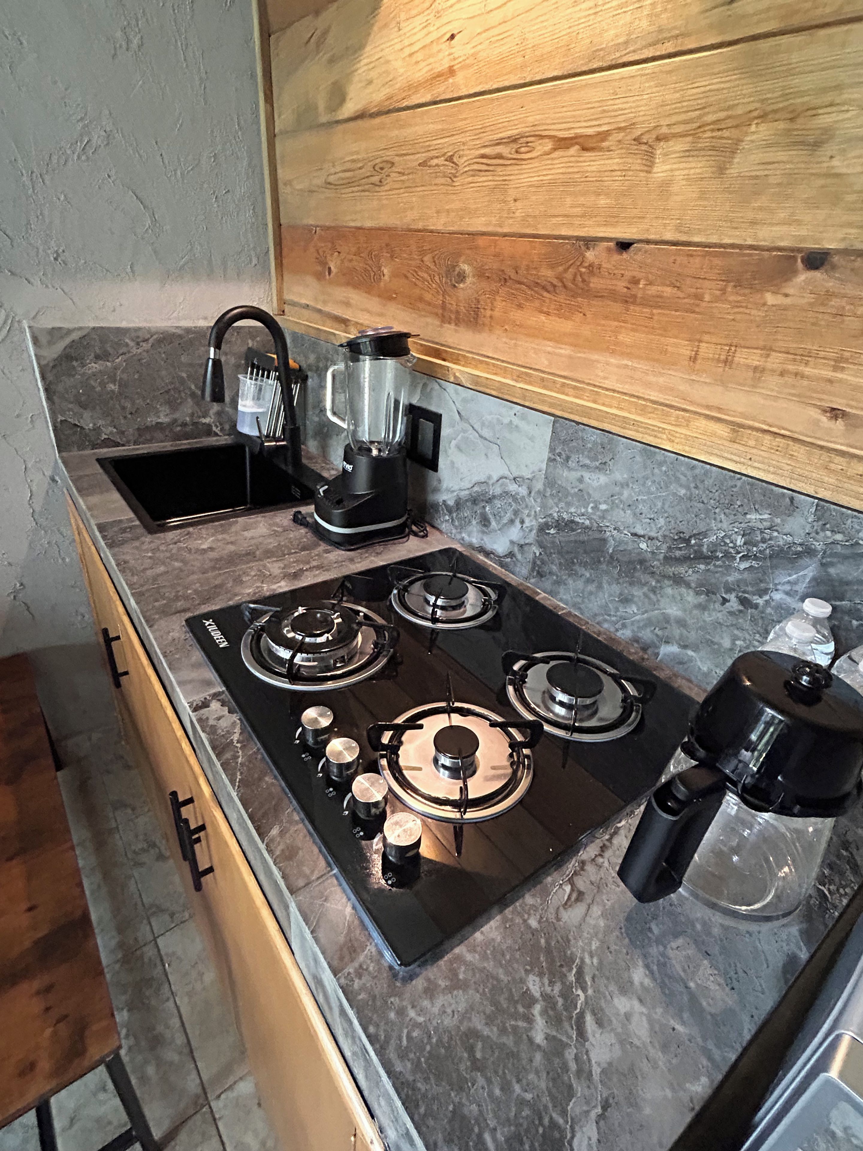 Una cocina con estufa a gas, un lavamanos y una cafetera.