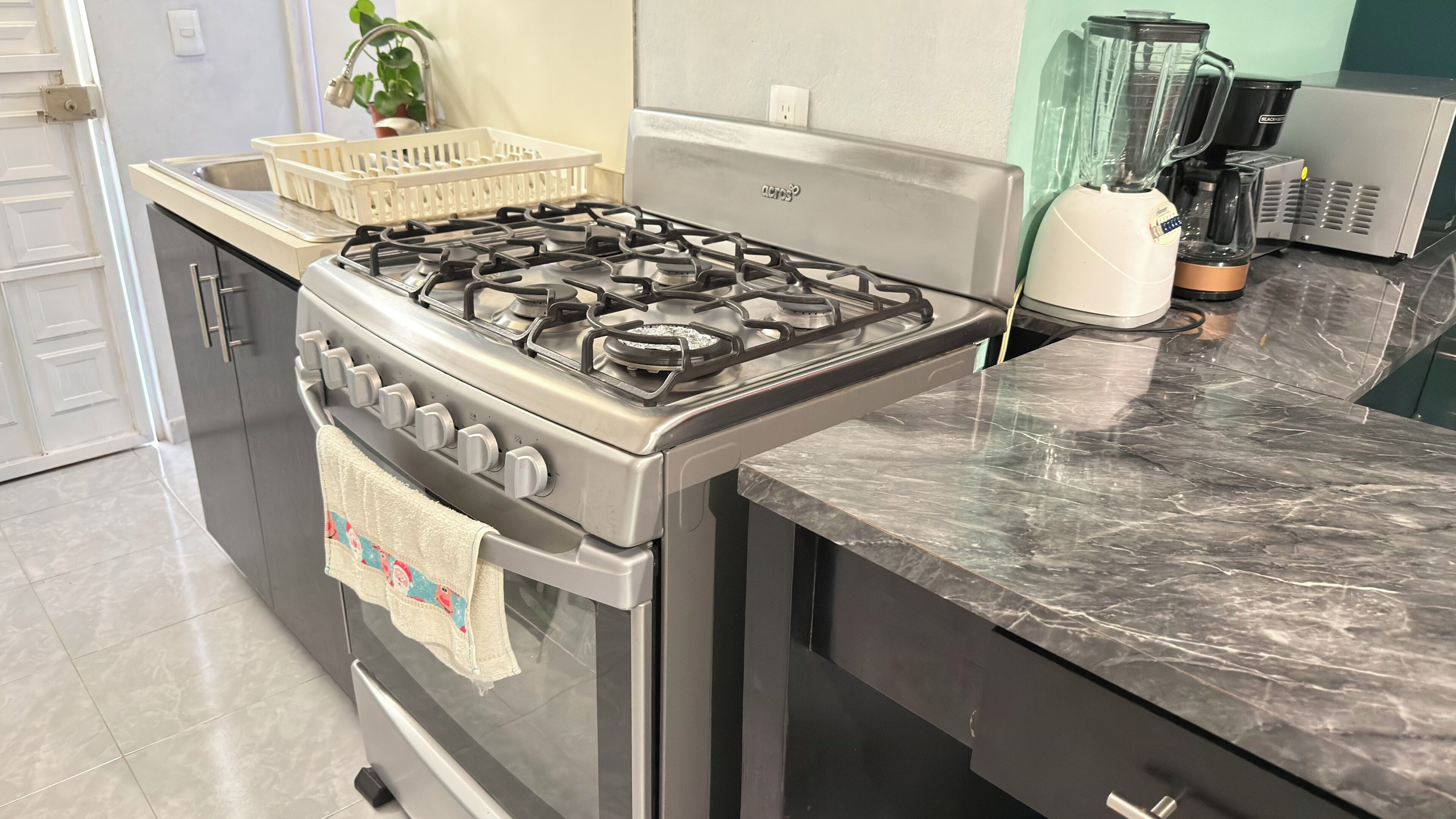 A kitchen with a gas stove, oven, and a coffee machine.