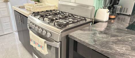 A kitchen with a gas stove, oven, and a coffee machine.