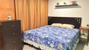 A bedroom with a bed, a dresser, a nightstand, a shelf with plants, and a window with curtains.