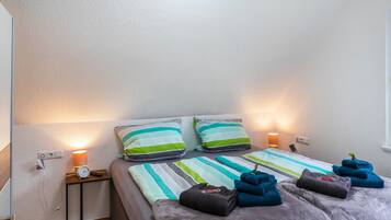 Une chambre d’hôtel avec deux lits, une literie à rayures, des oreillers, une table de chevet avec une lampe et des serviettes.