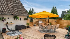 A wooden deck with outdoor furniture, a barbecue grill, and potted plants.