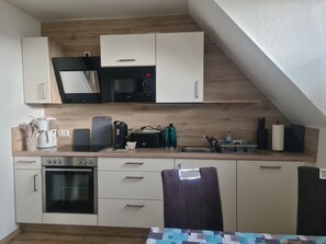 Ett kök med mikrovågsugn, kaffebryggare, brödrost och ugn.