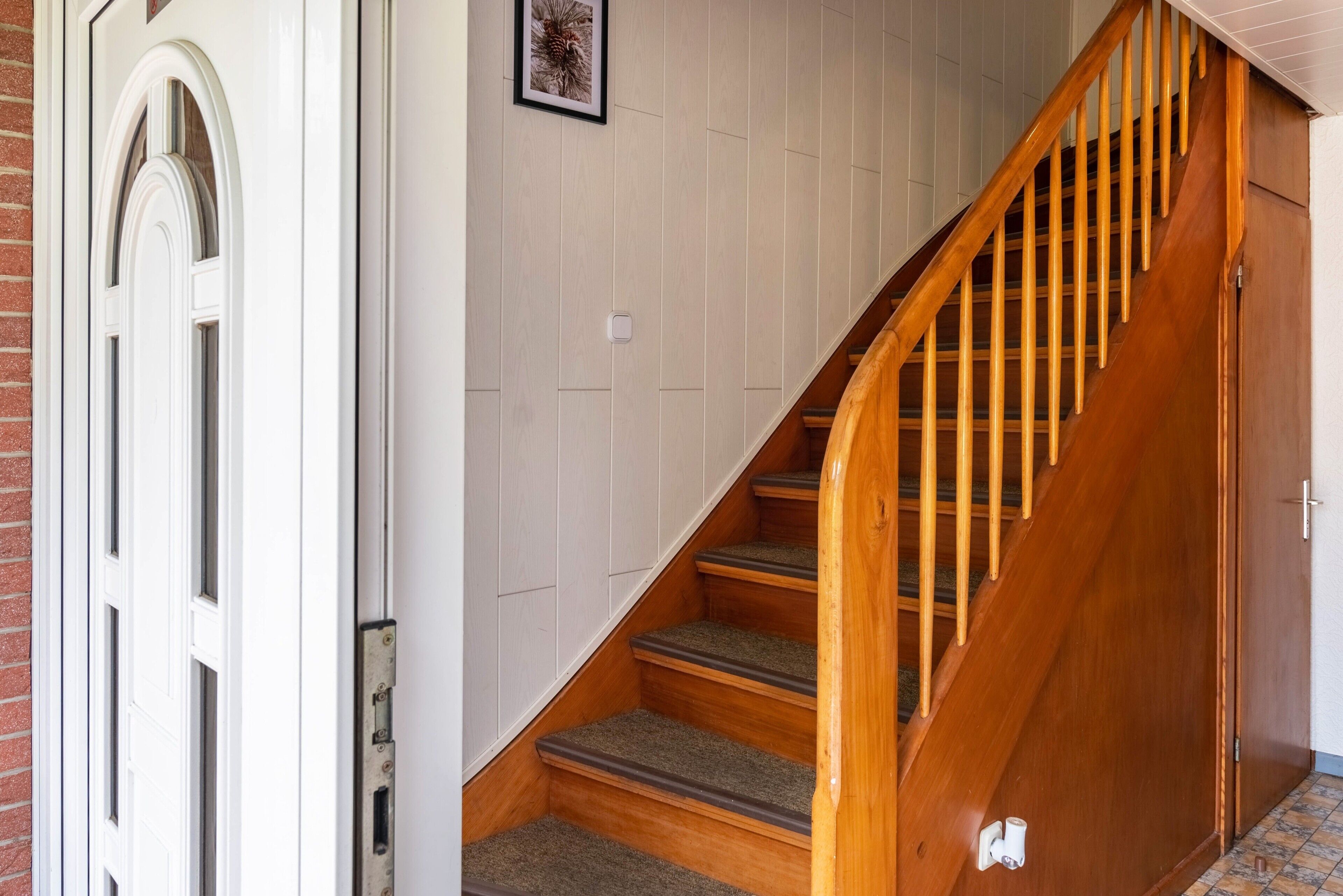 Eine Holztreppe mit Teppich belegten Stufen, die zu einer Zwischenebene führen.