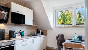 A modern kitchen with a built-in oven, a coffee machine, and a dining area with a table and chairs.