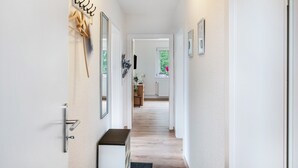 A hallway with a coat rack, a bench, and a door leading to another room.