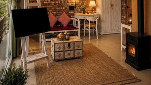 Una habitación acogedora con pared de ladrillo, chimenea, ventilador de techo y un ventanal con cortinas.