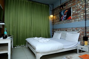 A bedroom with a bed, green curtains, a brick wall, and a painting. - Mystic Kailasha  (Ukhimath)