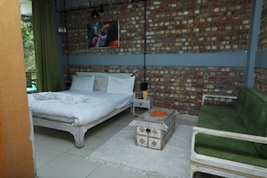 Une pièce avec un mur en briques, un lit, une chaise verte et une petite table.