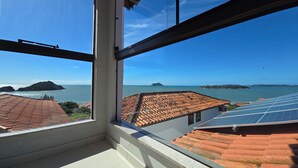 Vista da janela com vista para a área costeira, com telhados em terracota e painéis solares.