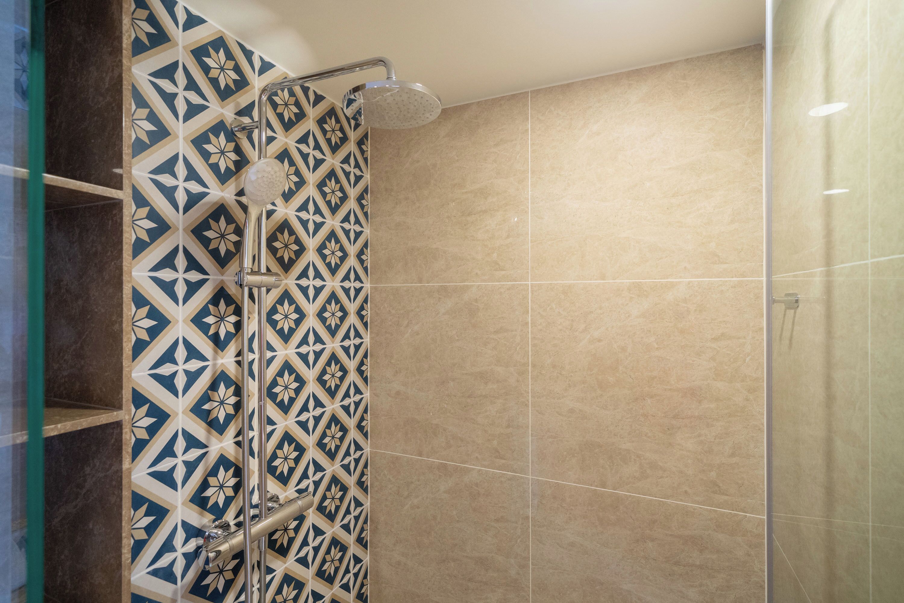 A shower with a geometric tile pattern and a glass enclosure.