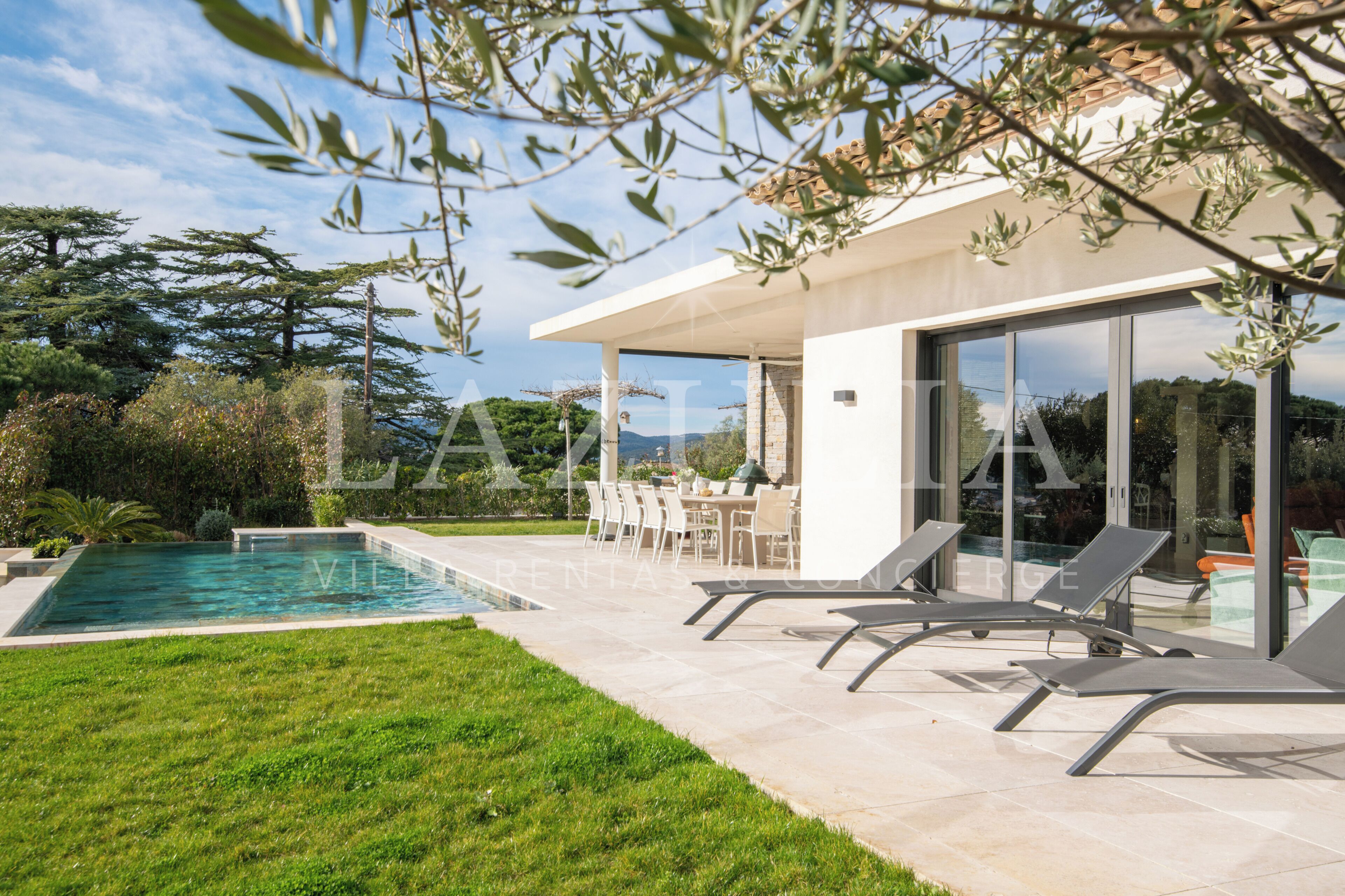 Area piscina moderna all'aperto con patio in vetro, posti a sedere esterni e vista sul paesaggio circostante.