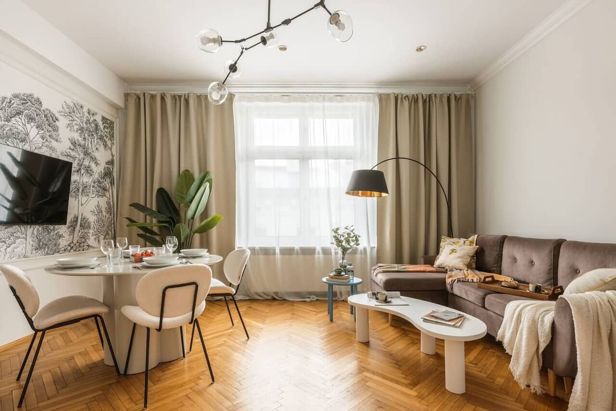 A modern living room with a dining area, a sofa, a coffee table, and a TV mounted on the wall.