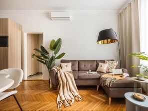 Una sala de estar moderna con un sofá, una mesita de centro, una lámpara y una planta en maceta.