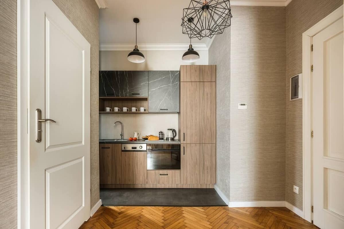 Une cuisine moderne avec des meubles en bois, un pare-feu en marbre et un parquet en bois disposé en chevrons.