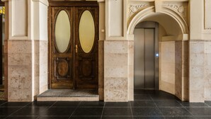 A grand entrance with a double wooden door, an elevator, and a light fixture above. - Florian Gate by Fragola Collection (Kraków)
