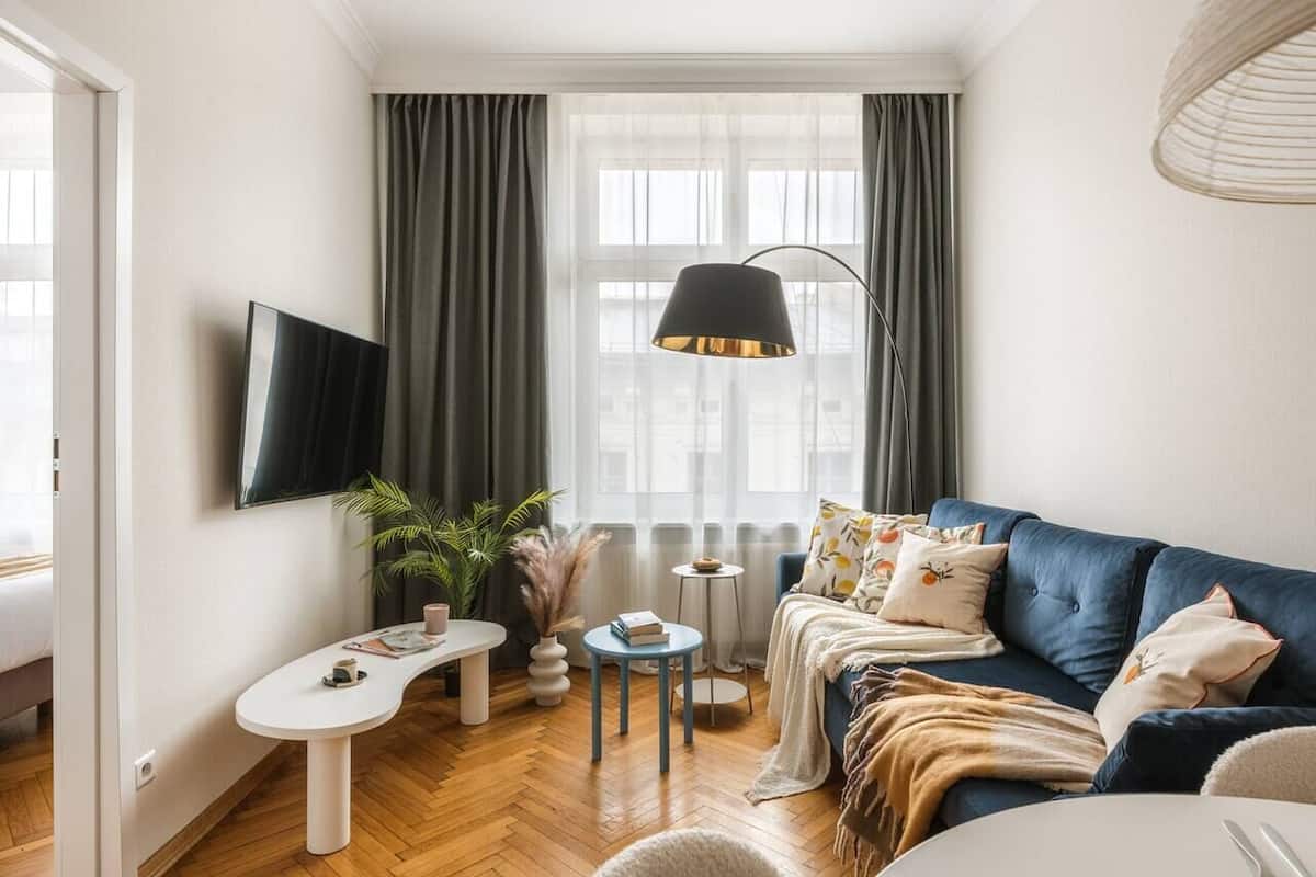 Un salon moderne avec un canapé, un téléviseur fixé au mur, une table ronde et un lampadaire.
