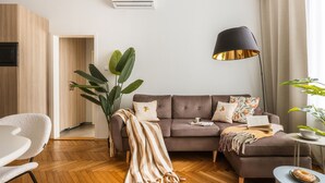 A modern living room with a sofa, a coffee table, a lamp, and a plant. - Florian Gate by Fragola Collection (Kraków)