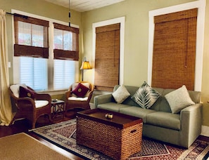 A living room with a sofa, armchairs, a coffee table, and a lamp. - Verdant Red Door Retreat (Galveston)