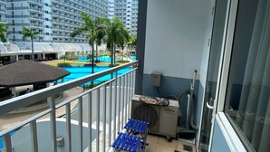 Un balcon avec vue sur la piscine, un ventilateur de plafond et une petite table avec des chaises.