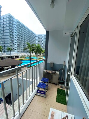 Ein Balkon mit Blick auf einen Pool, einem Deckenventilator und einem kleinen Tisch mit Stühlen.