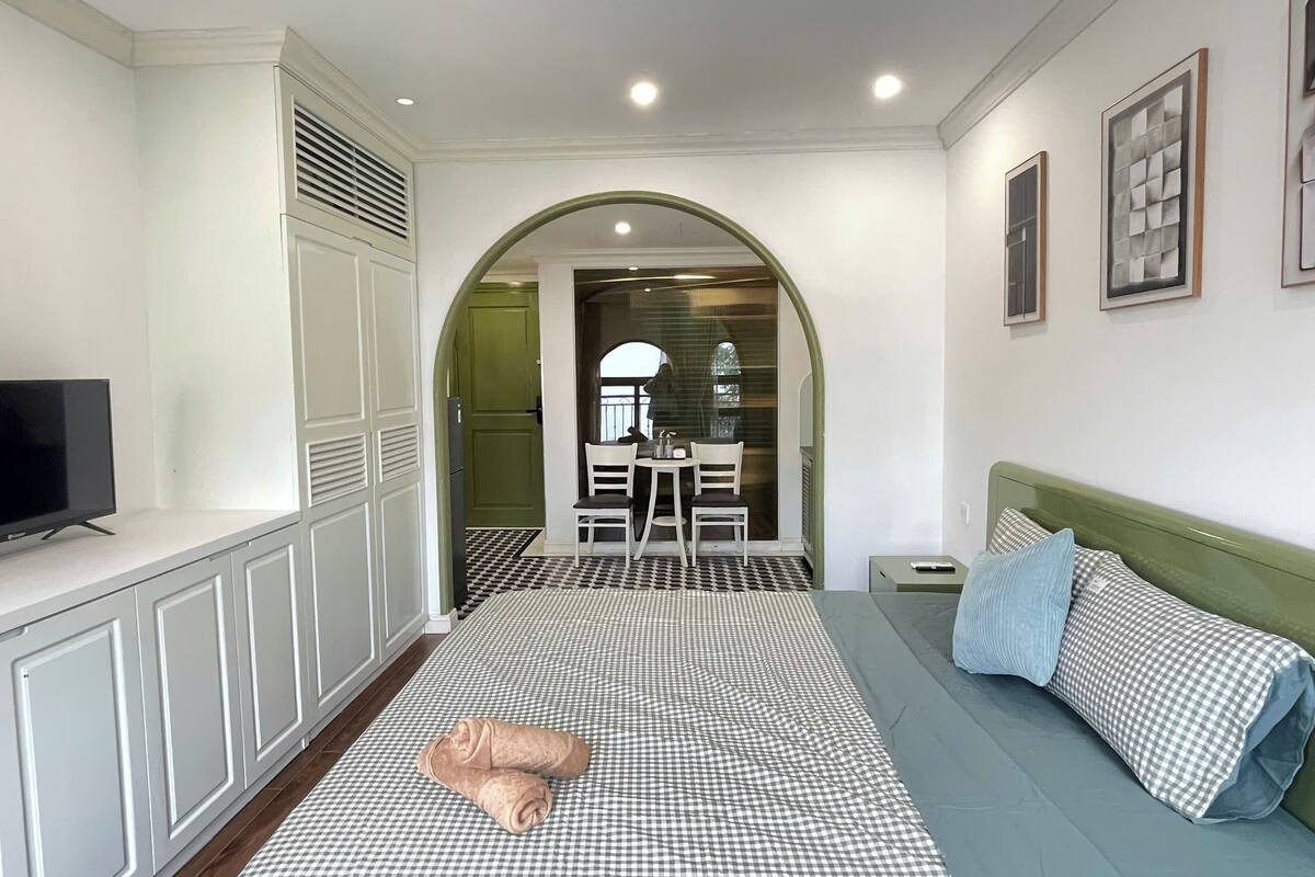 Un dormitorio con cama, televisor, escritorio y silla.