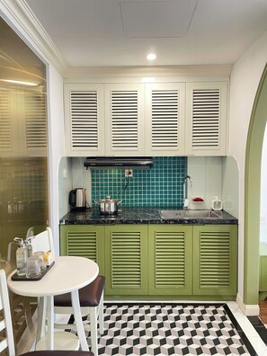 A kitchen with green cabinets, a black and white checkered floor, and a coffee maker on the counter. - Elegant Home - City View - Center (Ha Noi)