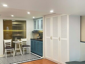 A compact kitchen with a dining area, a built-in stove, and a large white wardrobe with louvered doors. - Elegant Home - City View - Center (Ha Noi)