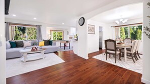 Un salon moderne avec un canapé, une table basse, une table à manger avec des chaises, et un coin cuisine à l’arrière-plan.
