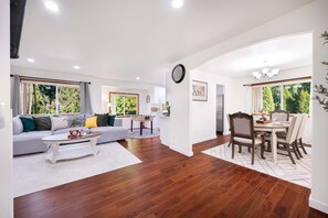 A modern living room with a sofa, coffee table, dining table with chairs, and a kitchen area in the background. - Private 3BR Greenbelt in Peaceful Lynnwood (Lynnwood)