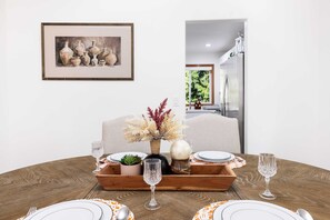 A dining table set with plates, cutlery, and glasses, a vase with dried flowers, and a framed painting on the wall. - Private 3BR Greenbelt in Peaceful Lynnwood (Lynnwood)
