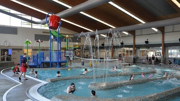 Une piscine intérieure dotée de plusieurs espaces de jeux aquatiques et d’une horloge au mur.