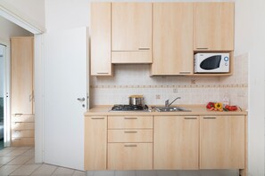 A kitchen with wooden cabinets, a microwave, a stove, and a sink. - Porto Letizia Bach 5, Porlezza, Italy (Porlezza)