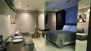 Een moderne hotelkamer met een bed, een bureau met stoel, een bank en een kleine tafel met lamp.