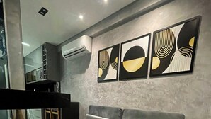 Een moderne woonkamer met een grijze bank, een ronde salontafel en abstracte wanddecoratie.