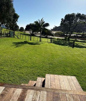 Un espace extérieur verdoyant avec une terrasse en bois, des arbres et une clôture.