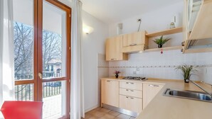 Una cocina moderna con un ventanal grande, armarios de madera, un lavamanos de acero inoxidable y una pequeña planta en la encimera.