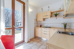 Eine moderne Küche mit einem großen Fenster, Holzschränken, einer Edelstahlspüle und einer kleinen Pflanze auf der Arbeitsplatte.