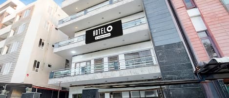 A multi-story hotel with a prominent 'HOTELO' sign, balconies, and a gated entrance.